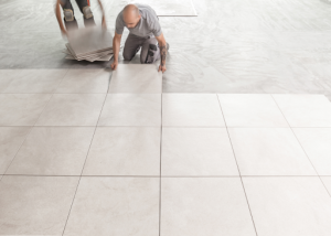 Seorang individu sedang memasang jubin lantai seramik bersaiz besar dalam susunan bercorak.